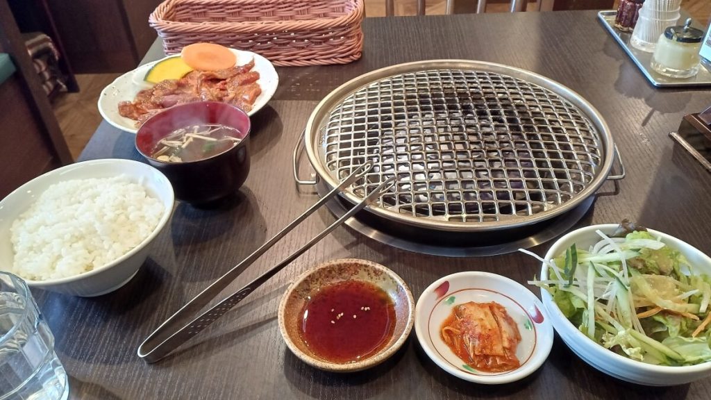焼き肉こぶたジンギスカン定食。焼き網、ごはん、肉、キムチ、野菜サラダ